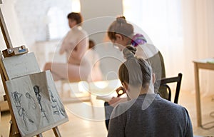 Young female artists sketching a nude model in drawing class