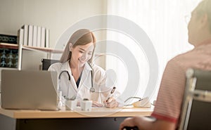 Young female Asian doctor smiling cheerfully talking to her patient during medical appointment communication interaction friendly photo