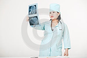 Young female Asian doctor with stethoscope looking at the x-ray. Nurse in a medical cap.