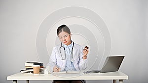 Young female Asian doctor working in her clinic room, whited isolated background