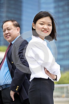 Young female Asian executive and senior Asian businessman smiling portrait