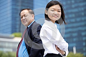 Young female Asian executive and senior Asian businessman smiling portrait