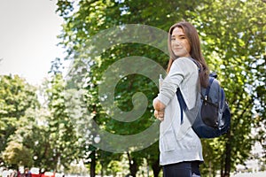 Young female asian IT student, with books and backpack. Staying in the park and smiling