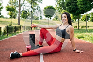 Young female athlete is casually sitting on the ground with her arm propped up