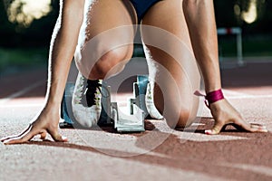 Young female athlete launching off the start line in a race.