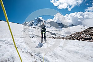 Young female Back view portrait Rope team member on acclimatization day dressed mountaineering clothes walking by snowy slopes in photo