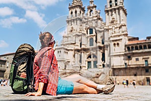 Young female backpacker piligrim sitting on the Obradeiro square plaza in Santiago de Compostela