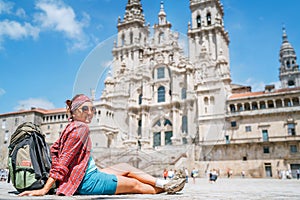 Young female backpacker piligrim sitting on the Obradeiro square plaza in Santiago de Compostela, Spain. Famous Camino de