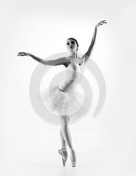 Young female ballet dancer on a light grey background