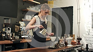 Young female barista in trendy modern cafe coffee shop pours boiling water over coffee grounds making a pour over drip photo