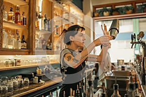 Young female bartender mixing cocktails behind a bar counter