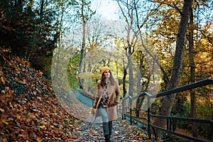 Young female in beige coat and orange hat walking