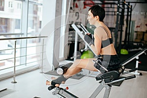 Young female bending over on gymnasium equipment