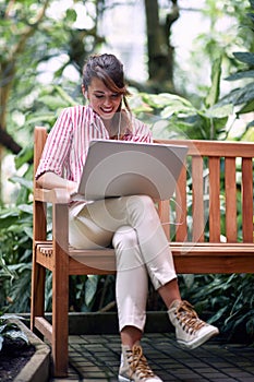 Young female biology student enjoying the work on the bench in a botanical garden