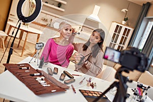 Beauty is all about you. Young female blogger, makeup artist applying makeup on middle aged woman face using cosmetic