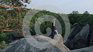 Young female in blue dress on edge of a cliff. Mystic pictures, ballet dancer stands on cliff end