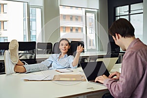 Young female boss communicating with her subordinate in open-plan office