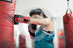 A young female boxer punching a bag in the gym