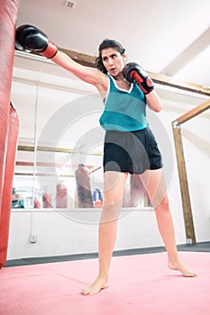 A young female boxer punching a bag in the gym