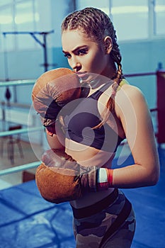 Young female boxer ready to fight in old leather boxing gloves. fitness happy blonde girl in sport wear with perfect body