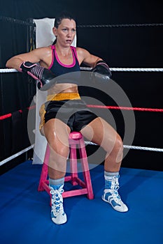 Young female boxer sitting on stool at corner