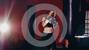A young female boxer starts beating at a punching bag.