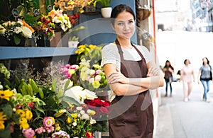 Young female business owner standing at her flower shop. Young entrepreneur leaning with her arms crossed and smiling confidently