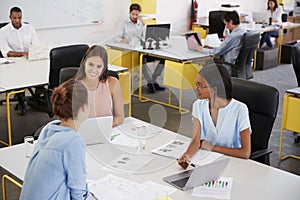 Young female business team brainstorming in busy office