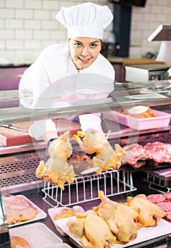 Young female butcher showing fresh gutted farm chickens