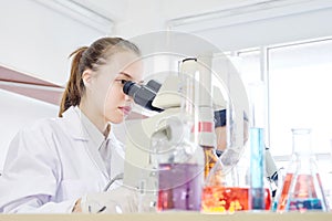 Young female cacausian Scientist researcher using microscope
