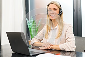 Young female call center operator with hands-free headset talking with client in home office. Concept of remote work