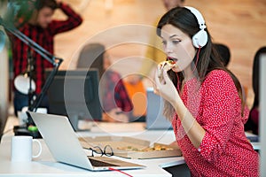 Young female in call center team eating pizza.