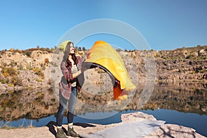 Young female camper with sleeping bag in wilderness