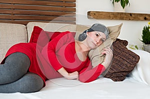 Young female cancer patient relaxing on a couch. Tired, exhausted, depressed cancer patient.