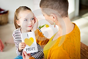 Young female cancer patient thanking her adorable young daughter for homemade I LOVE MOM greeting card. Happy Mother`s Day .