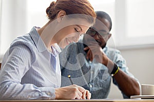 Young female candidate signing contract after successful interview in office