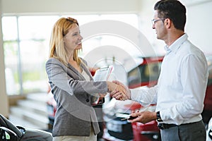 Young female car sales consultant working in showroom