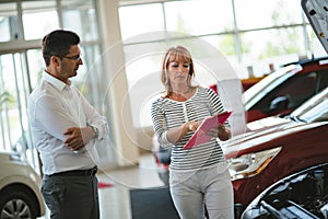 Young female car sales consultant working in showroom