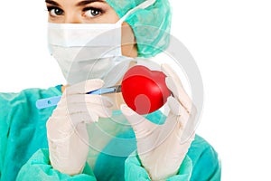 Young female cardiologist surgeron holding heart and scalpel
