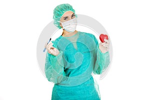 Young female cardiologist surgeron holding heart and scalpel