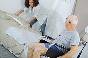 Young female caregiver helping senior man at home