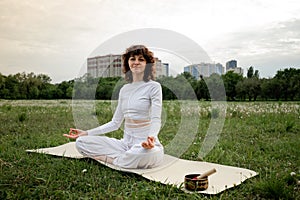 Young female on caremat put hands on lap. Pranayama practice. Concept of yoga meditation. Sports woman hobby relaxing