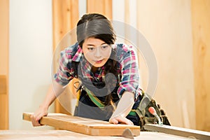 Young female carpenter cutting wood