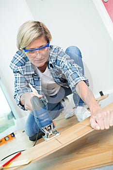 Young female carpenter using bandsaw in workshop