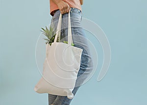young female carrying reusable cloth bag of fruits and vegetables  on blue background