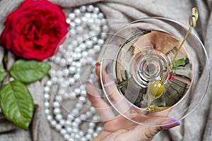 Young female caucasian hand holding a martini with olives, closeup, top view