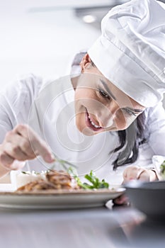 A young female chef finishes the meal with herbs in the restaurant kitchen - Close up