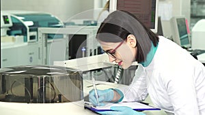 Young female chemist taking notes at the modern laboratory