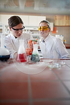Young female chemistry students in the university laboratory doing an experiment with chemicals. Science, chemistry, lab, people