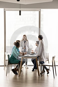 Young female chief doctor holding meeting with diverse medical team